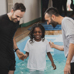 Young girl stands full of joy inside a baptism pool