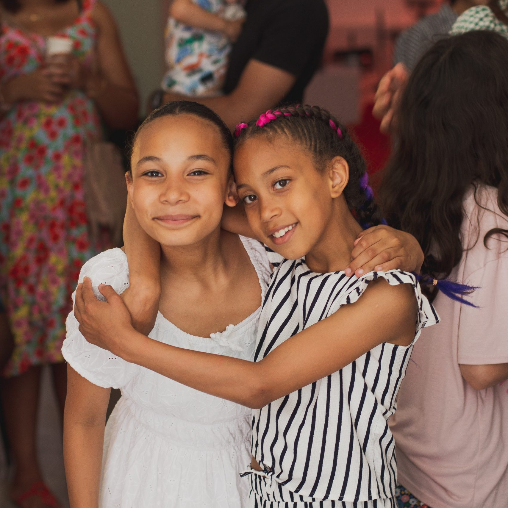 Two young sisters hug and smile together